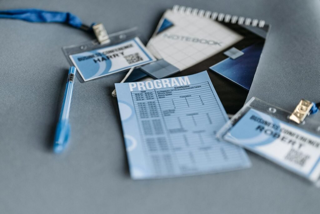 Close-up of conference materials including name tags, program, and pen on a gray surface.
